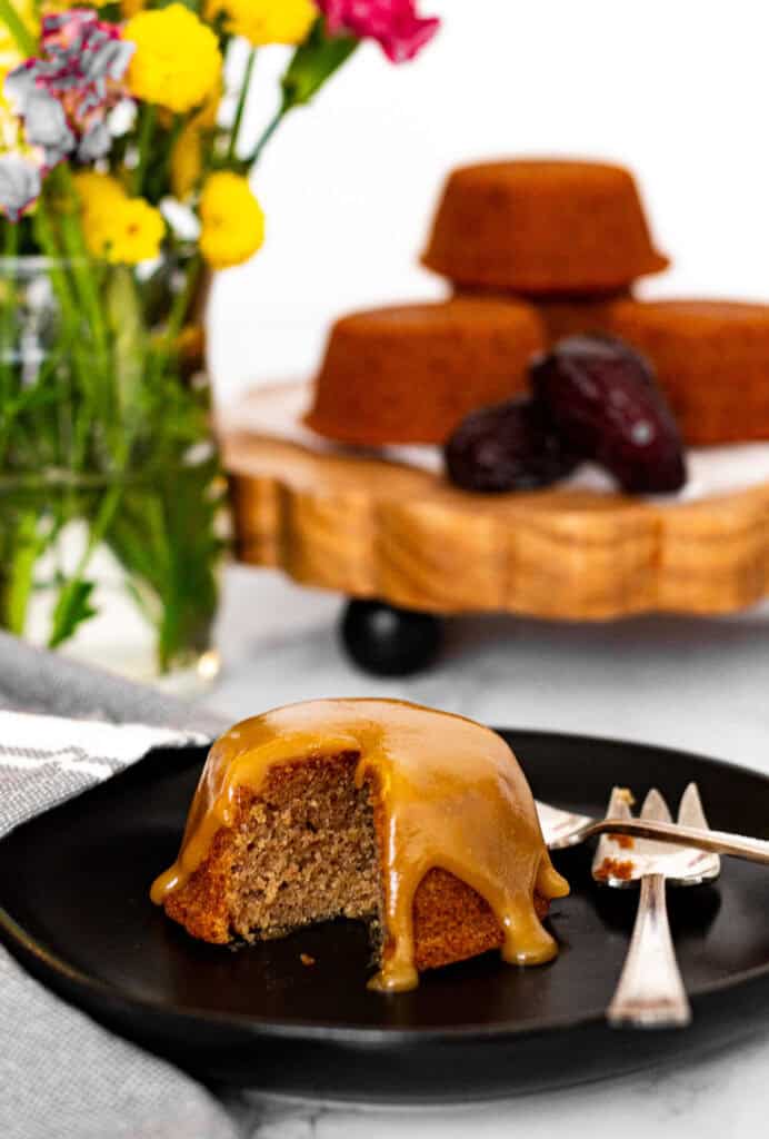 Sticky toffee pudding with bite showing soft moist texture and glossy toffee sauce