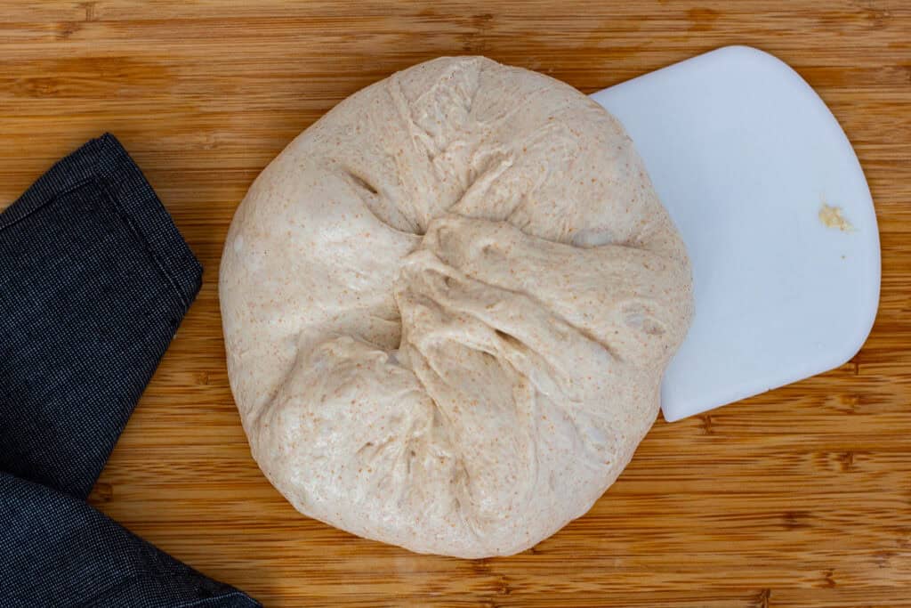 Bringing the edges of the dough toward the center to start forming a loose round." Photo 3 (flipped over, swiping upward to tighten the round) Title: Tightening the Preshape Alt Text: "Flipped dough being shaped into a round using an upward swiping motion to create surface tension." If you have the bench rest photo or the final shaping sequence next, go ahead and send them — we’ll keep everything consistent and beautiful.