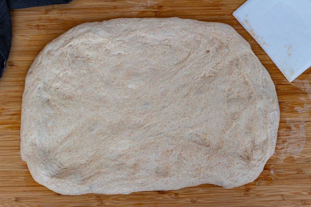 Dough gently flattened on the board before shaping the sourdough discard bread.