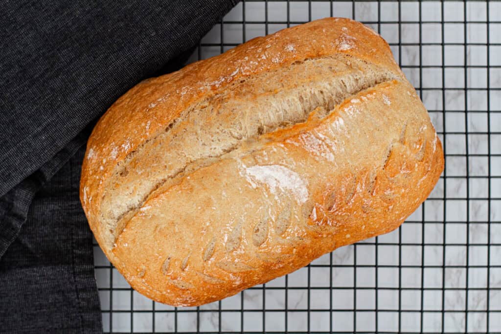 Golden sourdough discard loaf cooling on a wire rack after baking.