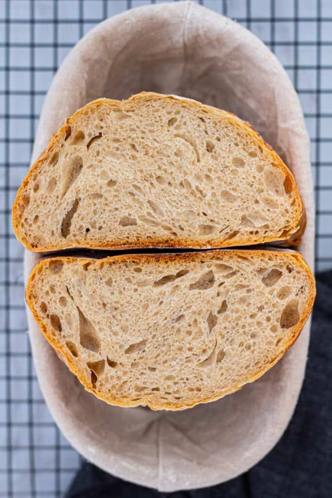 Cross-section of sourdough discard bread showing an even, airy crumb, displayed in a banneton.