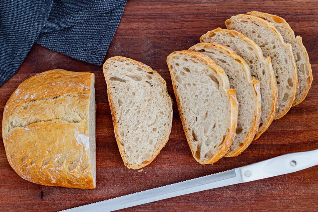 Sourdough discard bread sliced on a wooden cutting board with a bread knife.