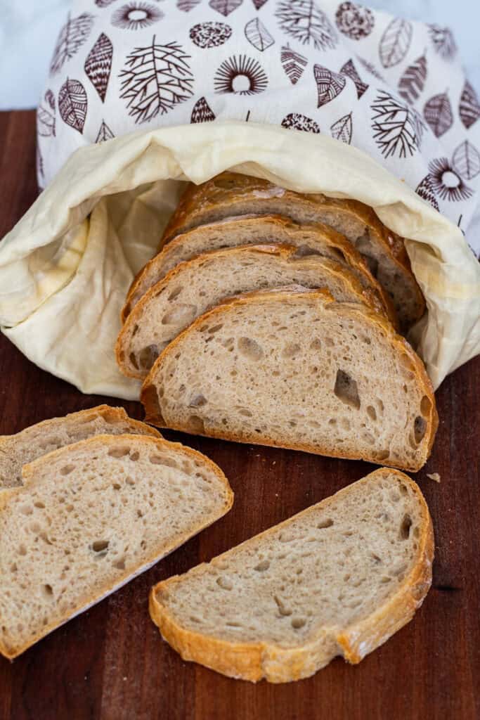 Slices of sourdough discard bread tucked into a reusable beeswax-lined bread bag for short-term storage.