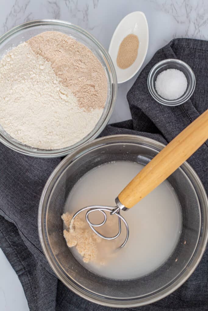 Ingredients for sourdough discard bread, including bread flour, whole wheat flour, yeast, salt, and water with sourdough discard mixed in.