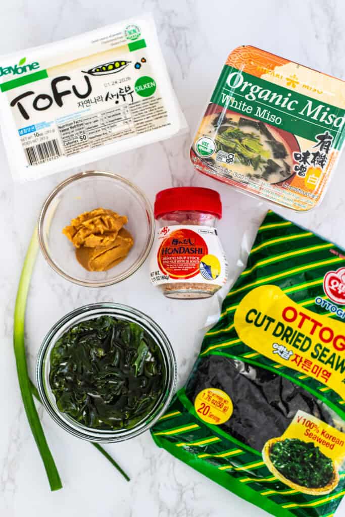 Ingredients for miso soup with dashi including white miso paste, silken tofu, wakame seaweed, and hondashi