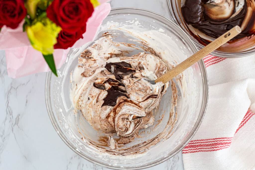 Chocolate mixture being folded into whipped cream to make light chocolate mousse