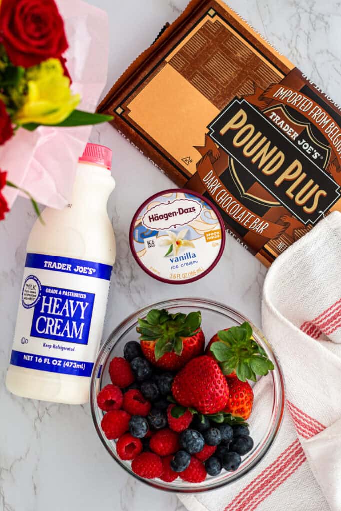 Ingredients for 3 ingredient chocolate mousse including dark chocolate, vanilla ice cream, heavy cream, and berries