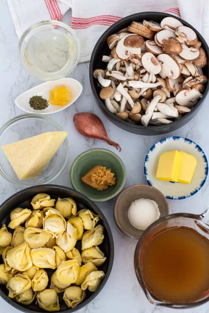 Ingredients for miso mushroom pasta including mushrooms, tortellini, miso, broth, and cheese