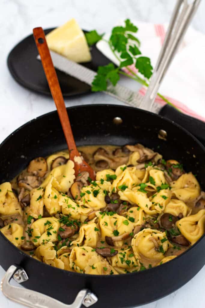 Skillet of creamy miso mushroom pasta with cheese tortellini and fresh herbs