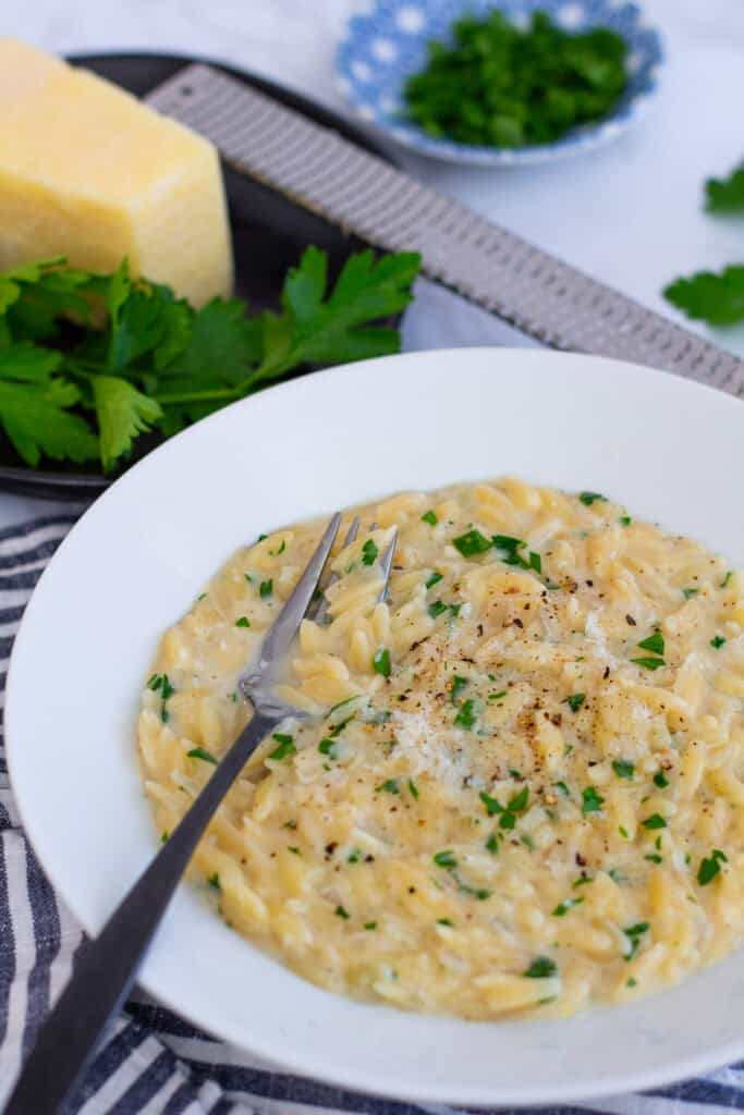 Creamy parmesan orzo served in a white bowl, finished with freshly grated parmesan and parsley