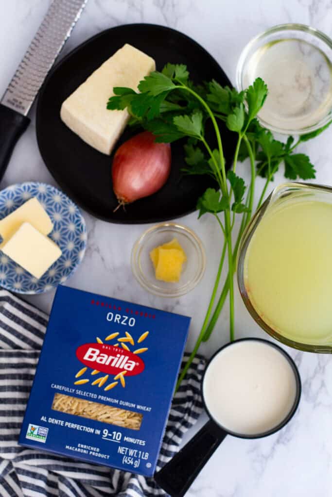 Ingredients for creamy parmesan orzo including orzo pasta, parmesan cheese, shallot, butter, cream, parsley, and broth
