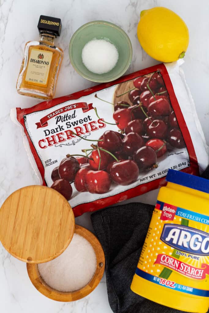Ingredients for cherry crisp including frozen cherries, amaretto, lemon, sugar, and cornstarch