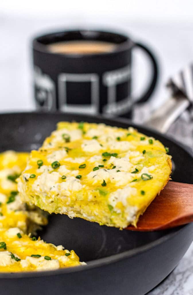 Slice of leek and Boursin frittata lifted from the skillet, showing tender interior.