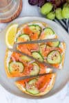 Smoked salmon flatbread topped with cucumber, red onion, and everything bagel seasoning, sliced and ready to serve.