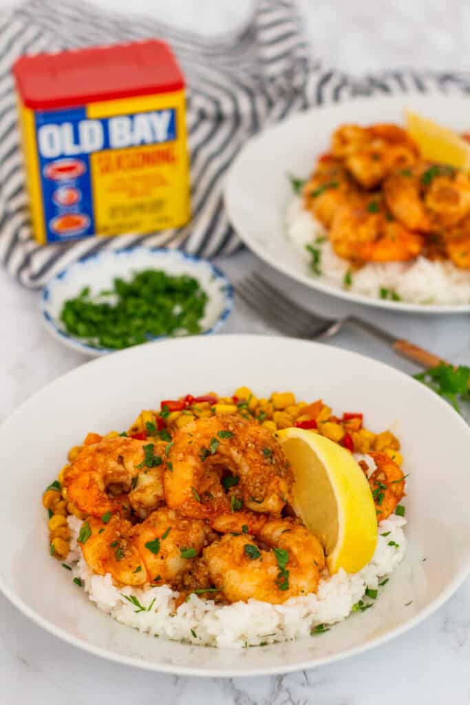 Spicy garlic butter shrimp served over white rice with sautéed corn and a lemon wedge.