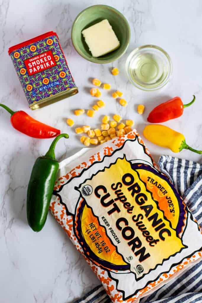 Overhead view of ingredients for sautéed corn including frozen corn, butter, oil, smoked paprika, and peppers