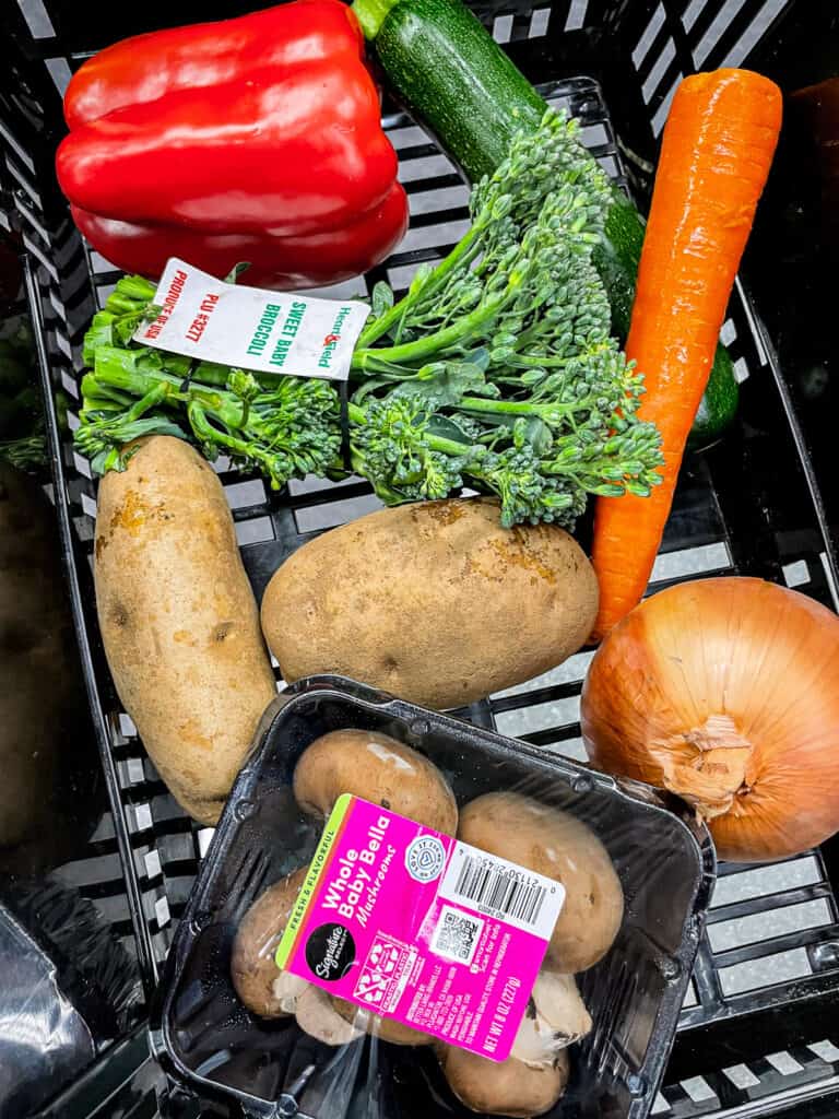 Assorted vegetables including bell pepper, zucchini, carrot, broccoli, potatoes, onion, and mushrooms showing realistic vegetable portions for cooking for two