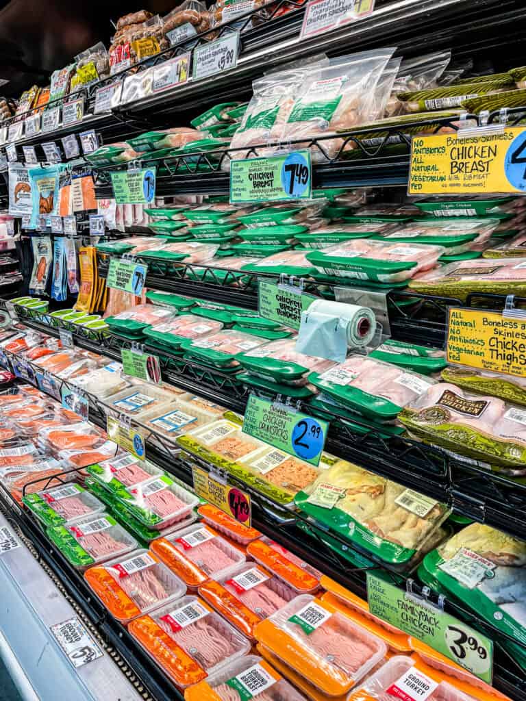 Grocery store meat section showing different protein options and package sizes to help plan how much food per person