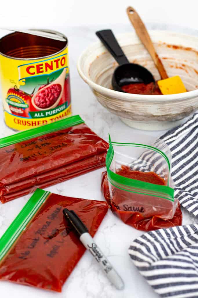Portioning homemade no cook pizza sauce into small freezer bags for later use