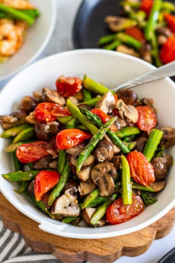 Close-up of roasted asparagus salad with mushrooms and tomatoes in vinaigrette