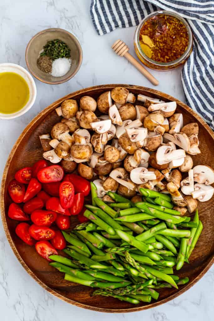 Fresh asparagus, mushrooms, and cherry tomatoes prepared for roasted asparagus salad