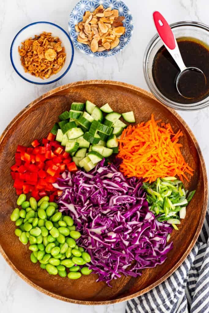 Ingredients for cabbage carrot salad including shredded cabbage, carrots, cucumber, and edamame