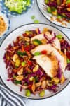 Cabbage carrot salad topped with sliced chicken, edamame, and fresh vegetables