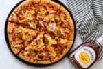 Homemade BBQ chicken and bacon pizza baked until golden brown and topped with sliced green onions.