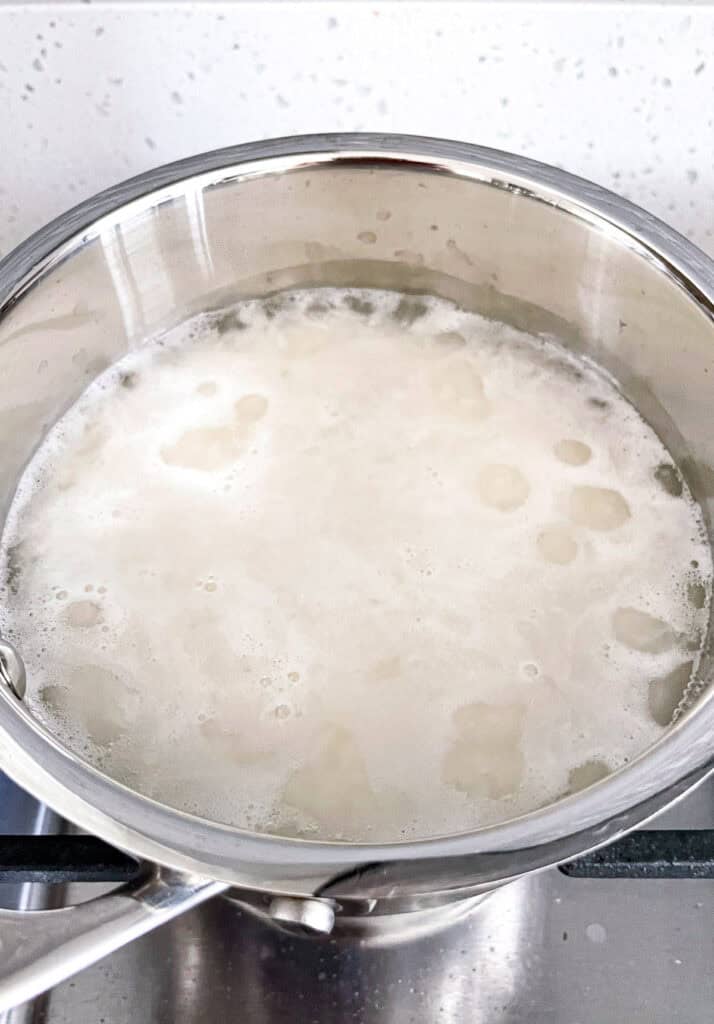 Jasmine rice simmering in a small saucepan before covering with a lid