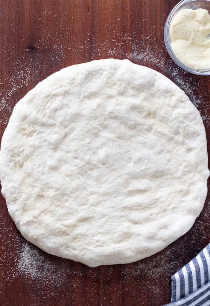 Small batch pizza dough stretched on a lightly floured surface.