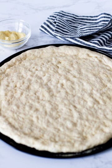 Small batch pizza dough shaped into a 10- to 12-inch crust on a pizza pan before adding toppings.