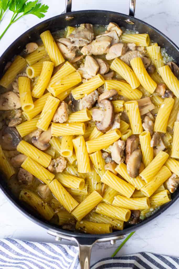 Rigatoni, chicken, and mushrooms cooking together as the broth reduces