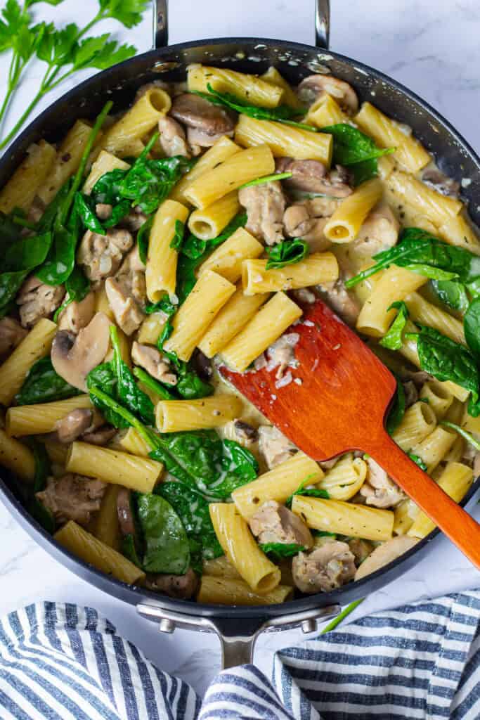 Creamy Boursin chicken pasta with mushrooms and wilted spinach in a sauté pan