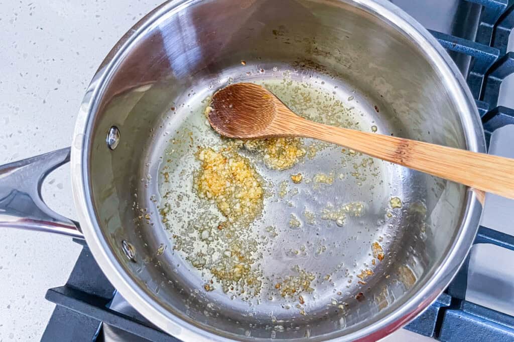 Minced garlic cooking in olive oil until lightly golden in a saucepan