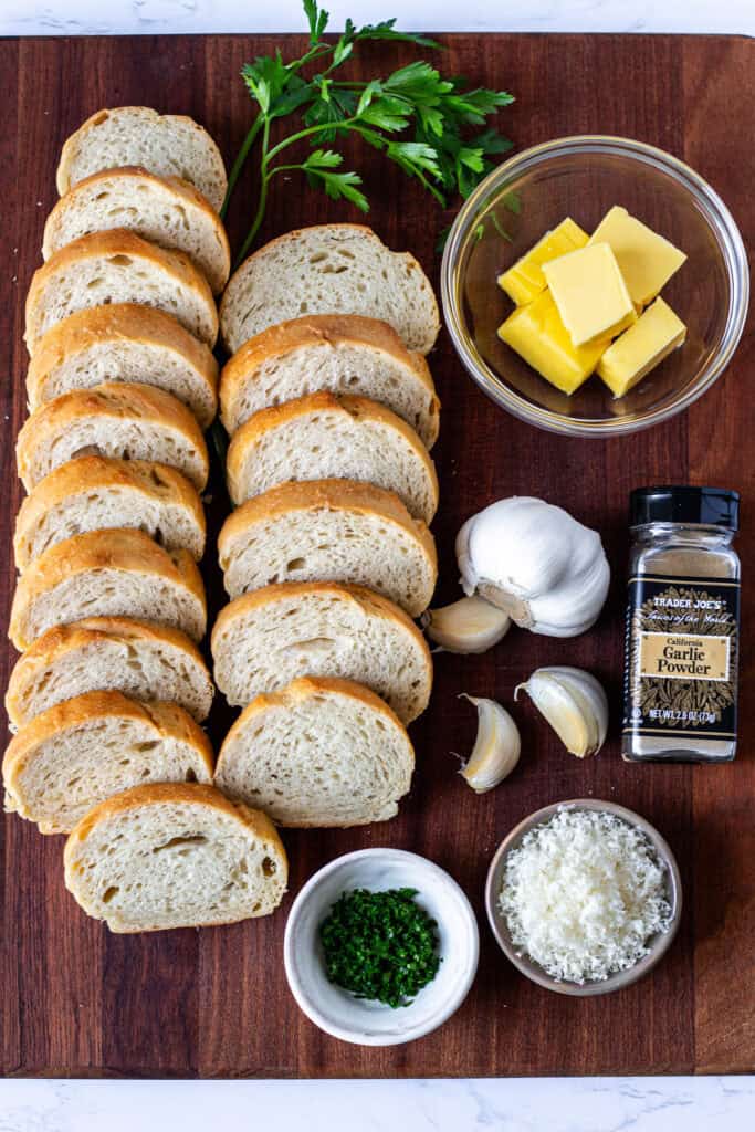 Sliced French bread with butter, fresh garlic, garlic powder, parsley, and grated Parmesan for homemade garlic bread
