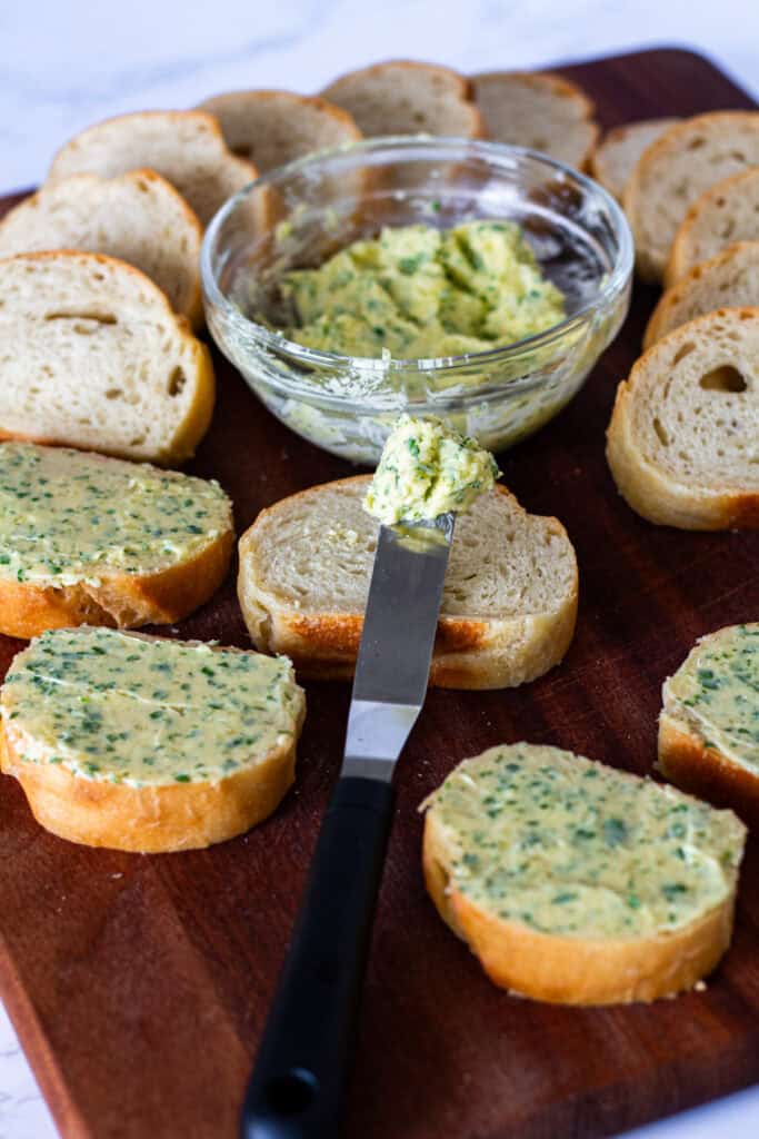 Spreading garlic Parmesan butter over slices of French bread