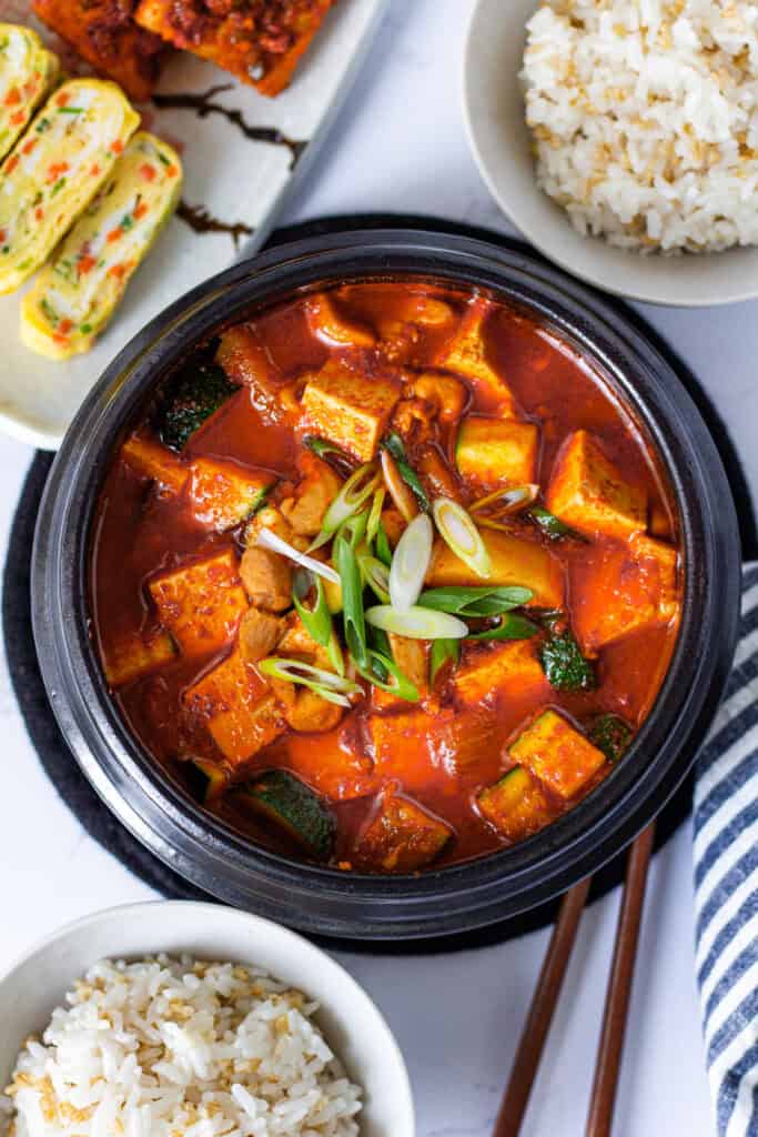 Overhead view of gochujang jjigae served with rice and Korean banchan