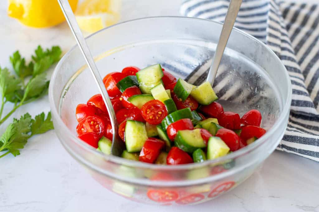 Fresh cucumber tomato salad tossed with olive oil, lemon juice, salt, and pepper for Greek turkey bowls.