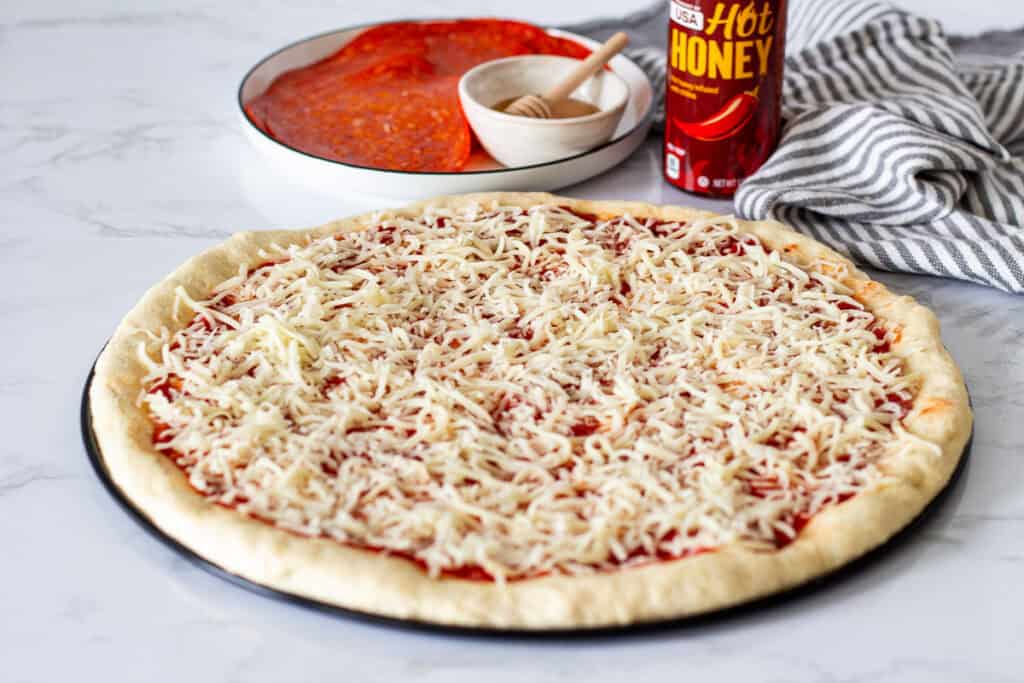 Pizza dough topped with pizza sauce and shredded mozzarella cheese