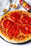 Close-up of sliced hot honey pepperoni pizza with red pepper flakes and hot honey