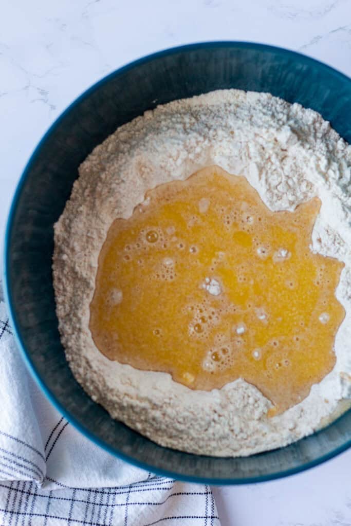 Wet ingredients added to whole wheat and all-purpose flour to make honey wheat bread dough