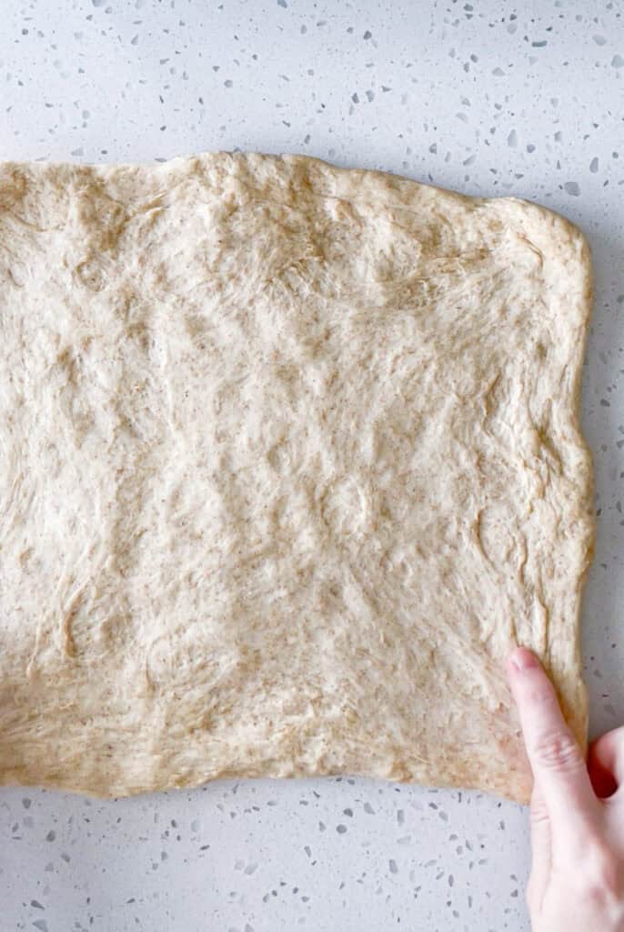 Honey wheat bread dough gently pressed into a rectangle before shaping the loaf