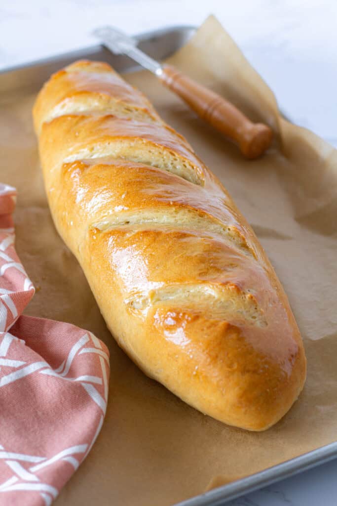 Freshly baked sourdough discard French bread with a golden crust brushed with melted butter.