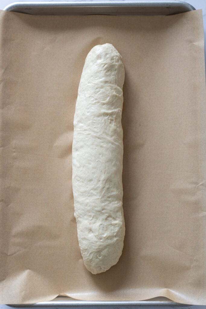 Sourdough discard French bread dough shaped into a long loaf before the second rise.