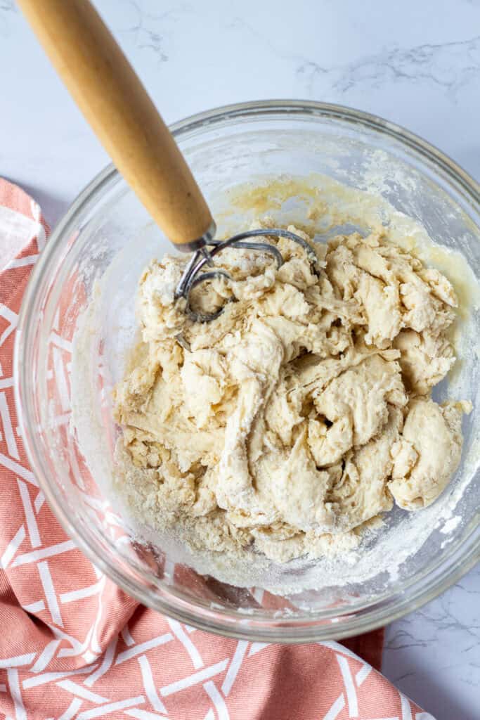 Sourdough discard French bread dough partially mixed in a glass bowl with some dry flour remaining.