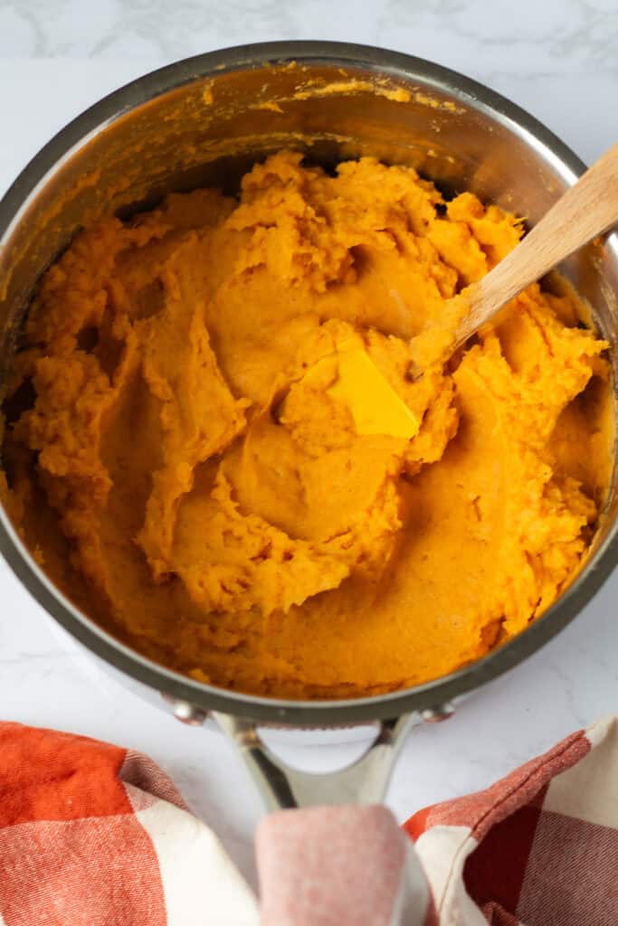 Creamy mashed sweet potato filling mixed with butter, brown sugar, cream, vanilla, and cinnamon, ready to transfer to a baking dish.