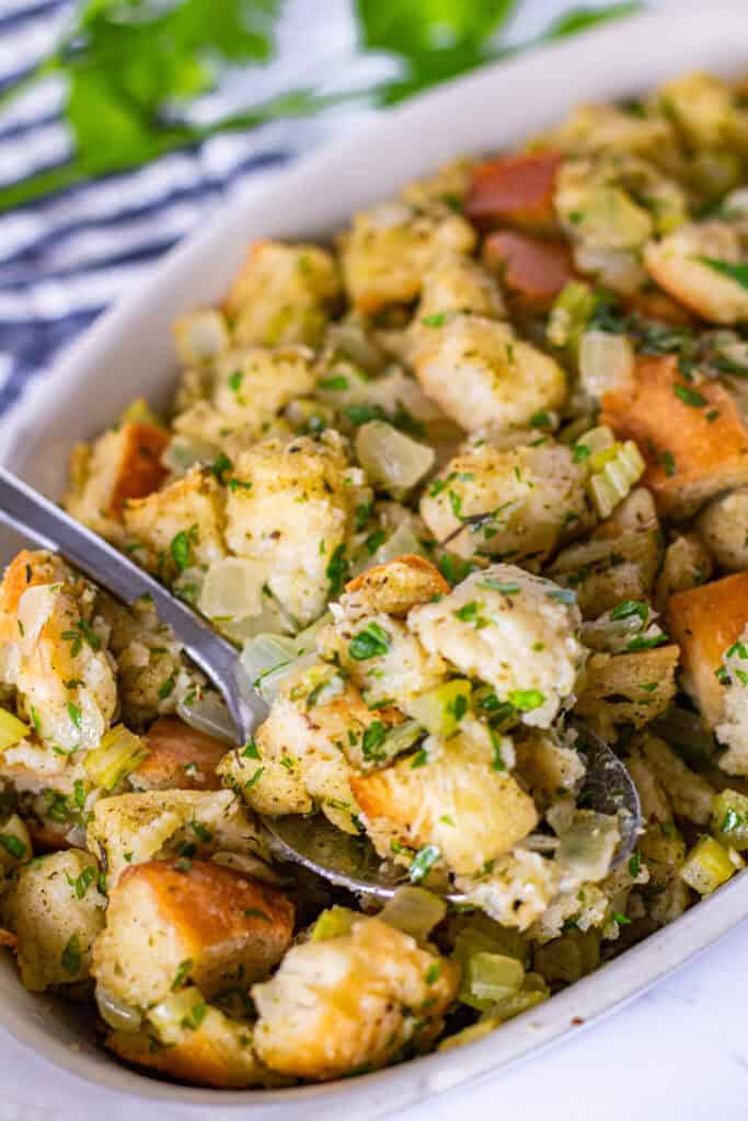 Close-up of homemade bread stuffing with golden edges, tender bread cubes, sautéed vegetables, and fresh parsley.