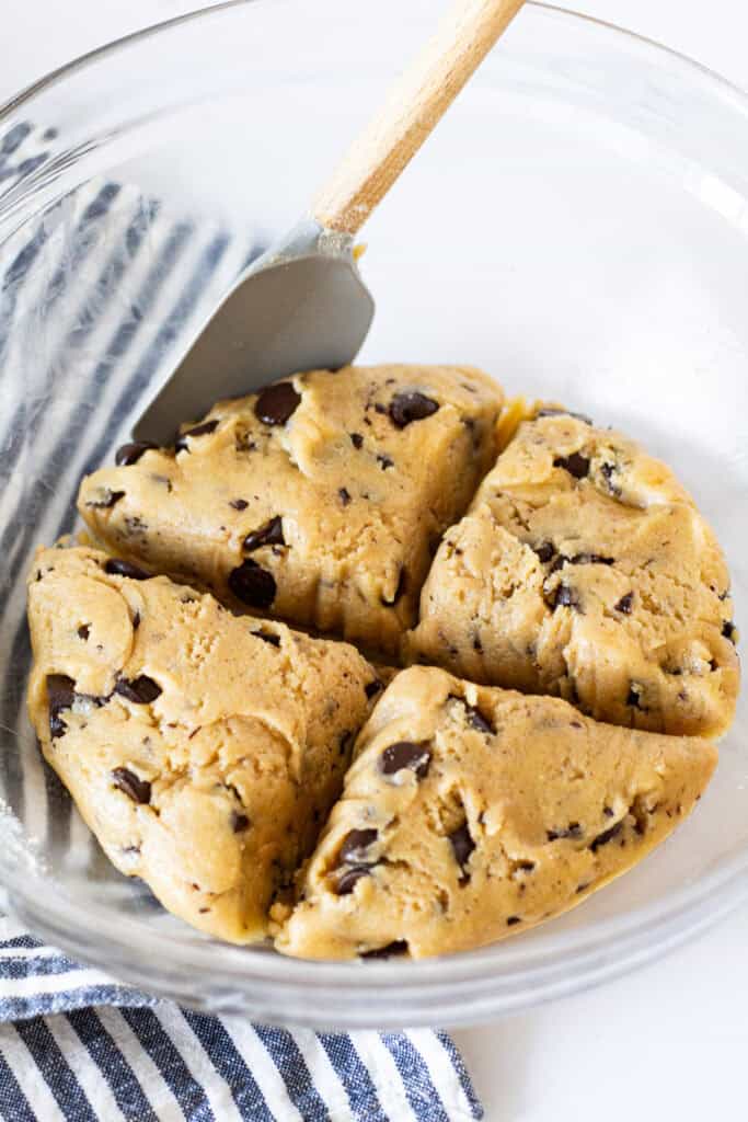 Chocolate chip cookie dough divided into four equal portions in a mixing bowl